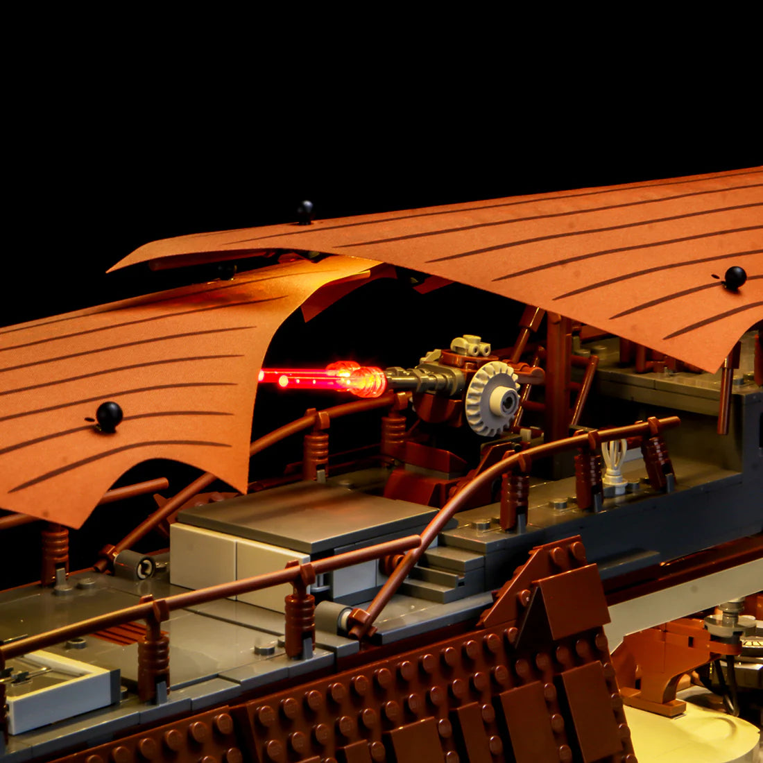 Detailansicht eines Lego Segelschiffmodells mit beleuchteter Kanone unter einem braunen Segeldach