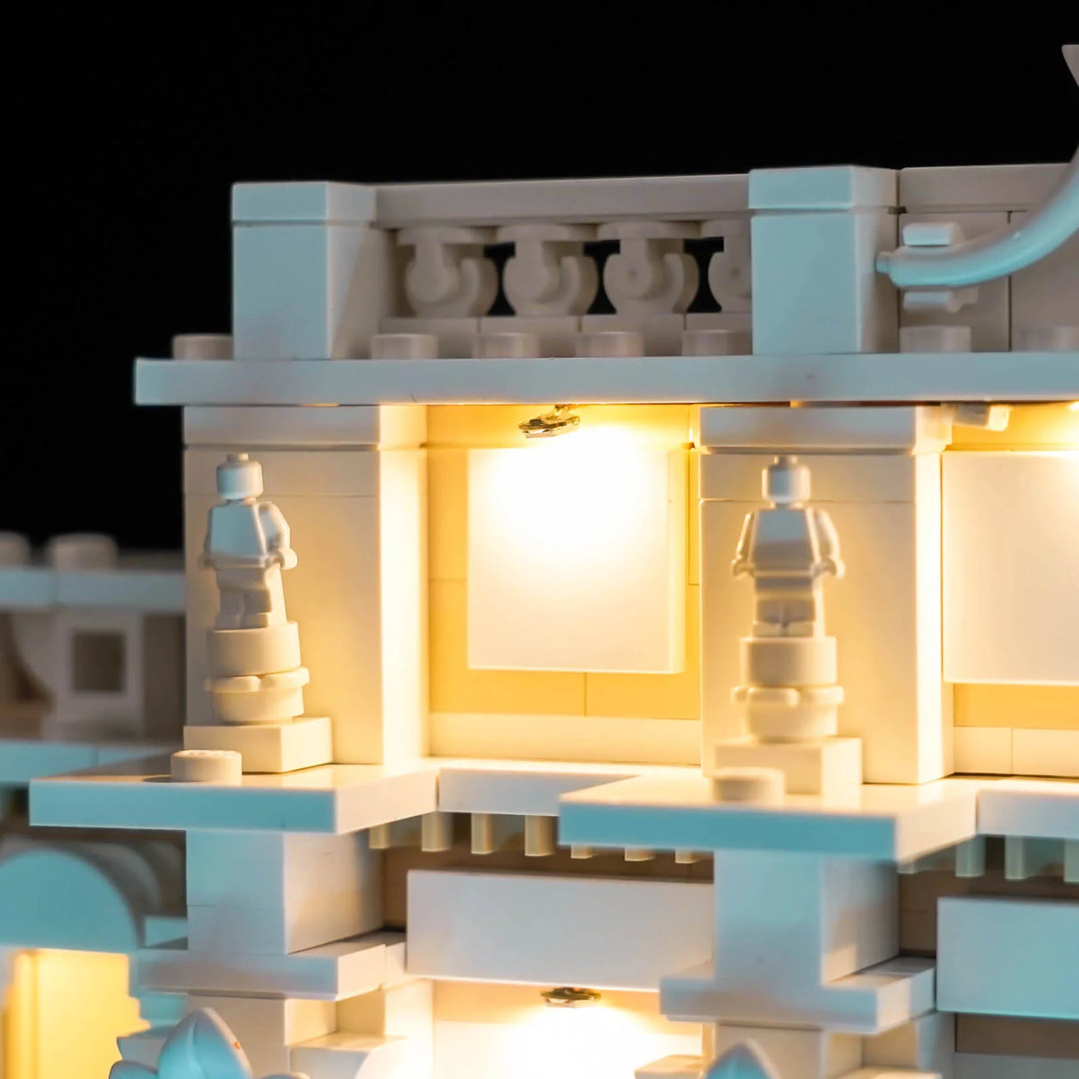 Nahaufnahme eines beleuchteten LEGO-Modells mit kleinen Statuen und einem Balkon