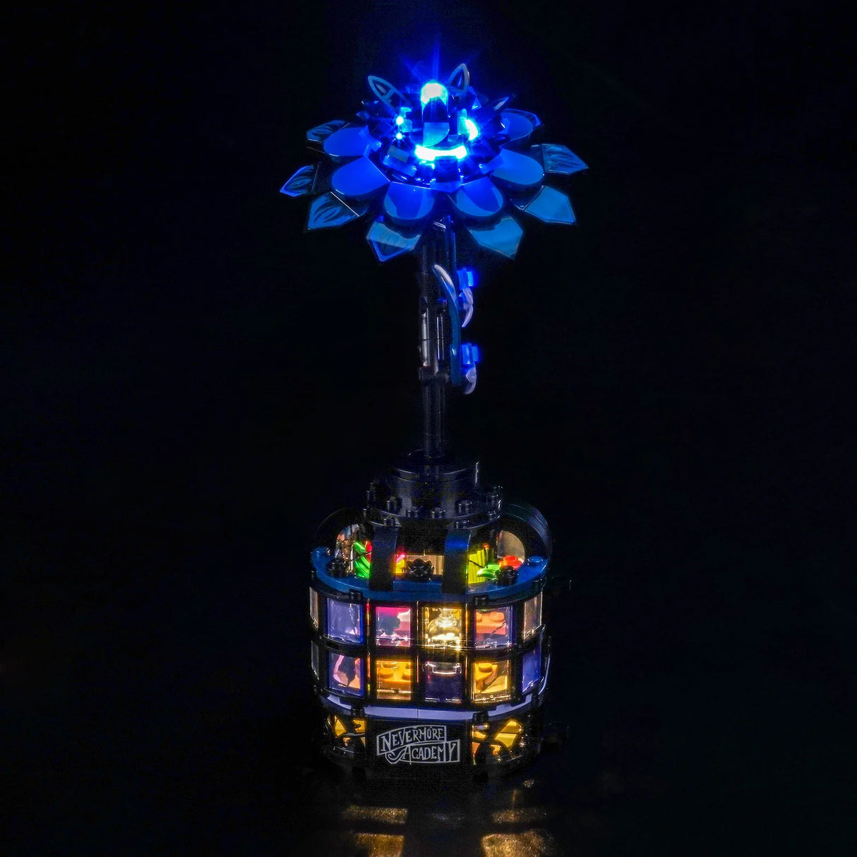 Ein beleuchtetes LEGO-Modell der Nevermore Akademie mit einer leuchtend blauen Blume oben
