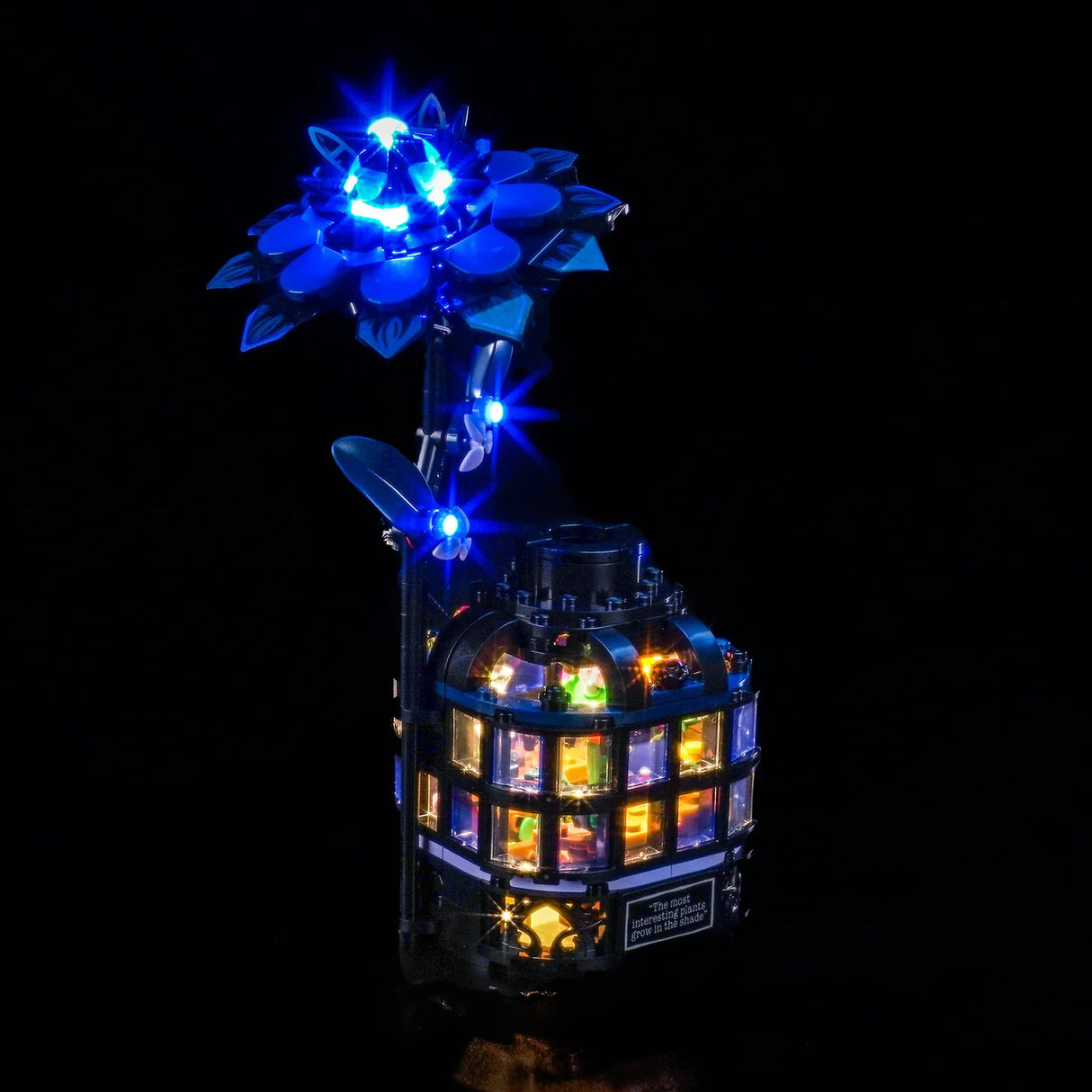 Ein LEGO-Modell einer blauen Blume mit leuchtenden blauen Lichtern und einem runden Gebäude mit bunten Lichtern