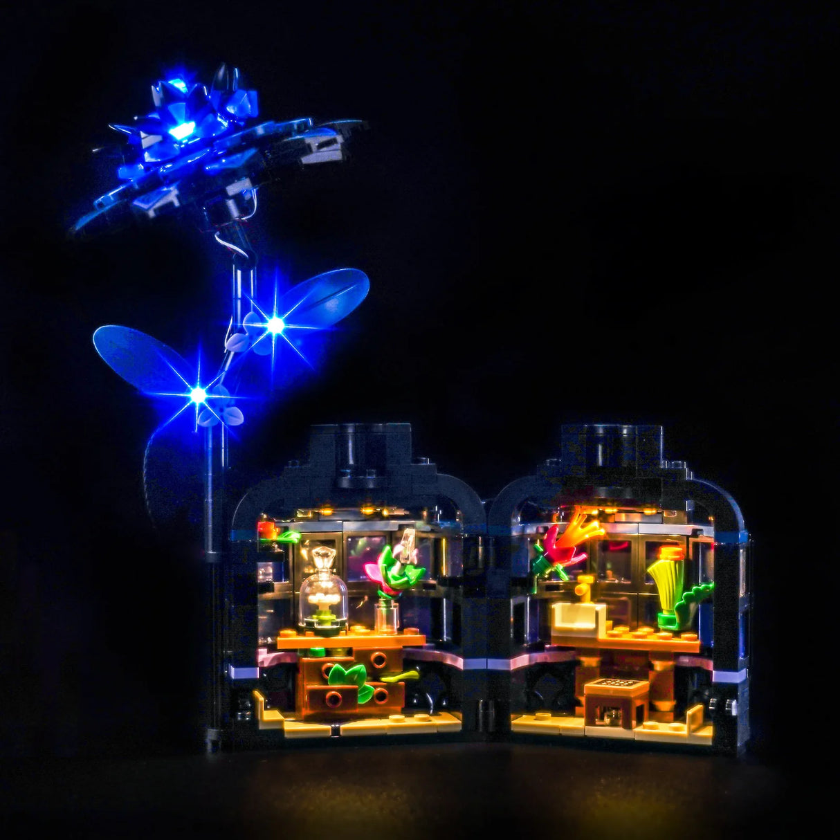 Ein beleuchtetes LEGO-Set mit einer blauen Rose und zwei Gebäuden mit Pflanzen und Möbeln
