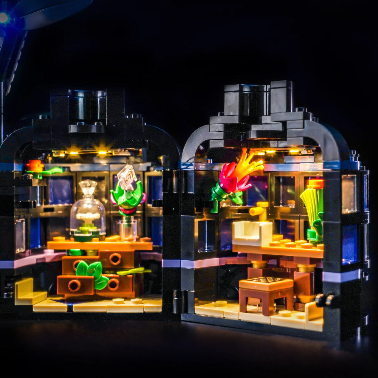 Zwei beleuchtete LEGO-Modelle mit Pflanzen und Möbeln auf schwarzem Hintergrund
