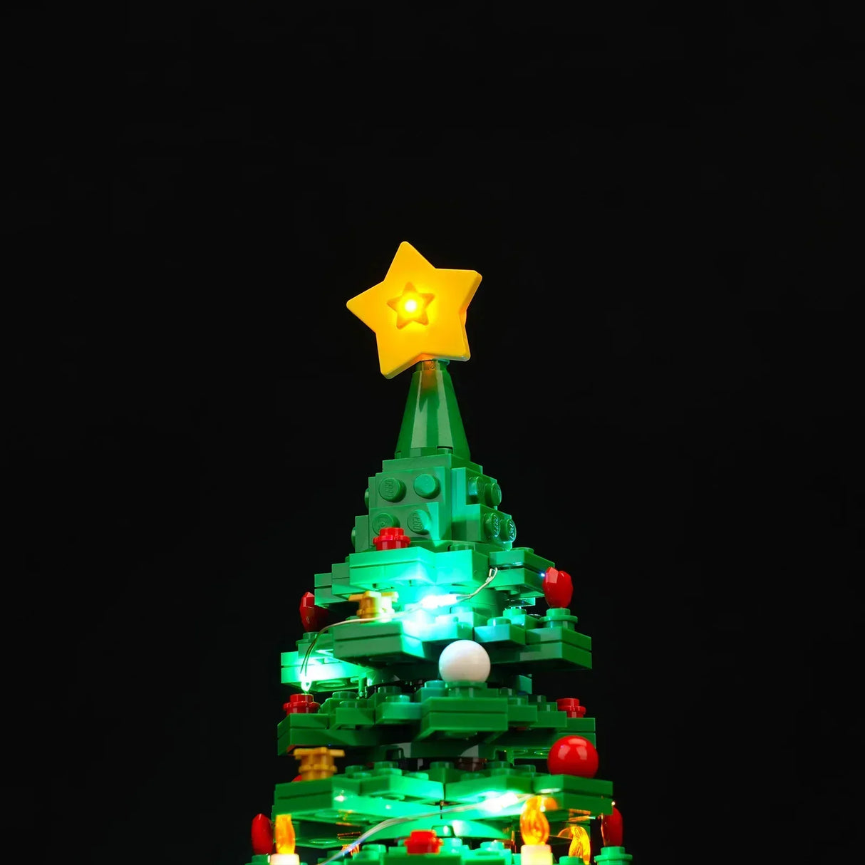 Beleuchteter Weihnachtsbaum aus Klemmbausteinen mit gelbem Stern an der Spitze vor schwarzem Hintergrund