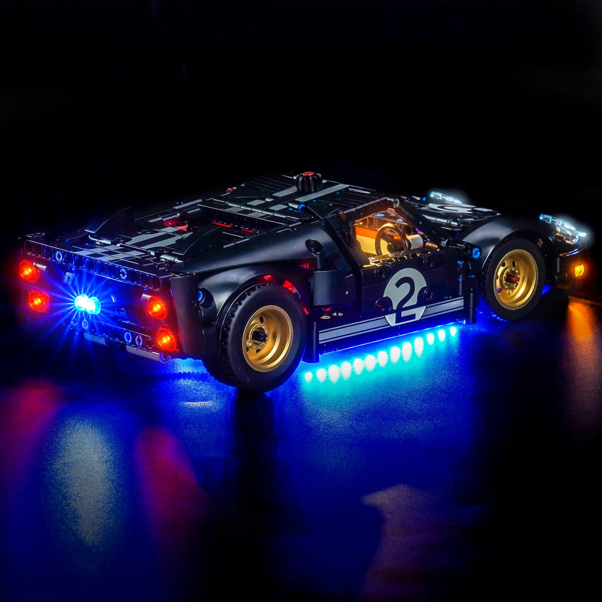 Schwarzes Lego-Auto mit leuchtenden roten Rücklichtern, blauen Unterbodenlichtern und weißen Scheinwerfern
