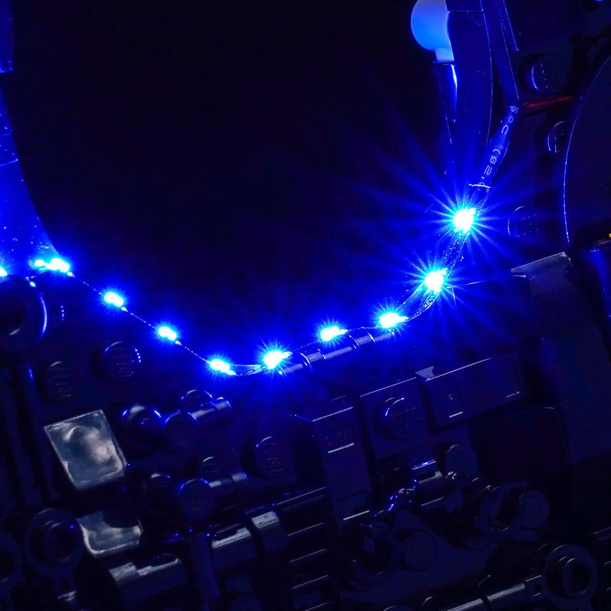 Nahaufnahme eines blauen LED-Lichtstreifens, der um ein dunkles, kompliziertes Objekt gewickelt ist