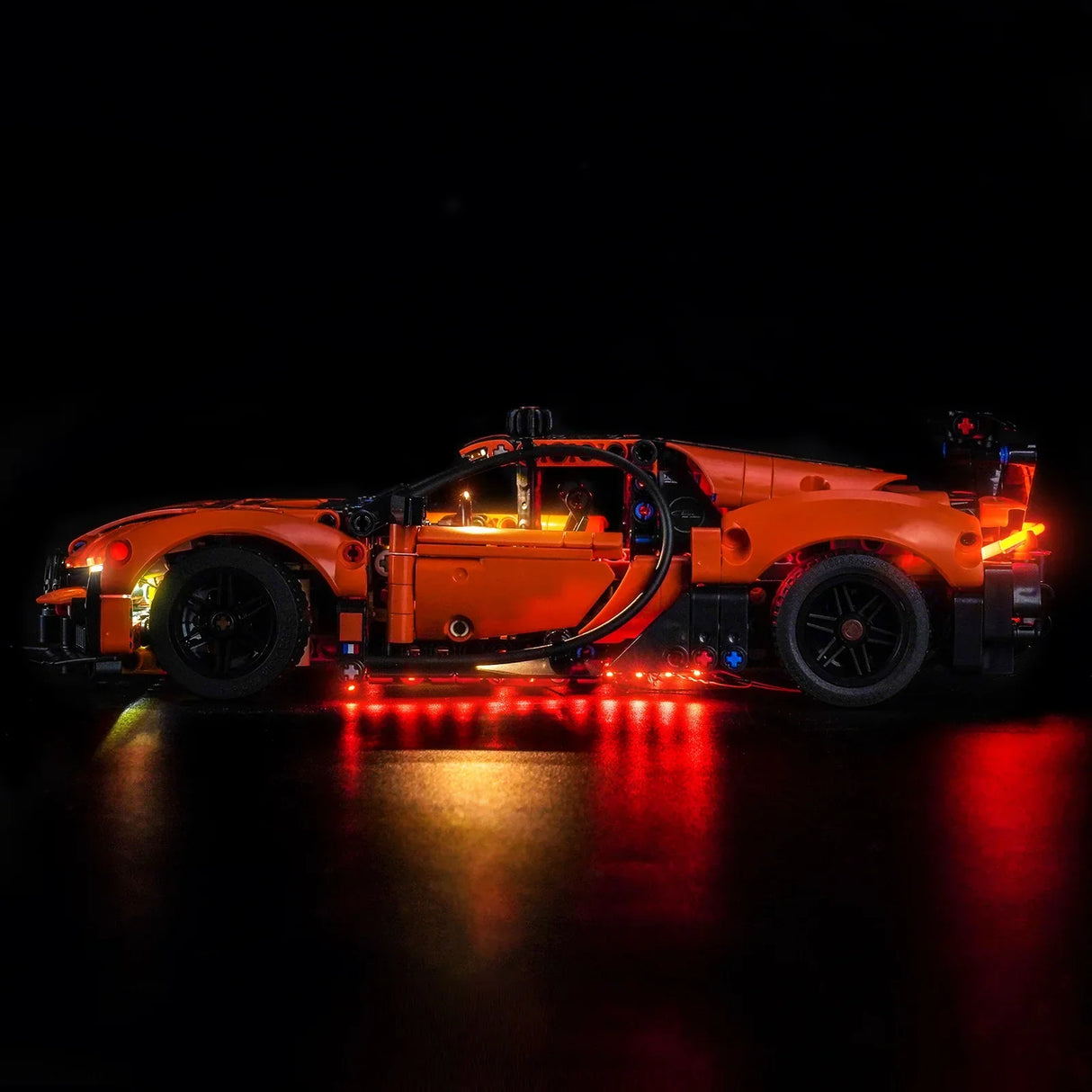 Orangefarbenes Lego Technic Auto mit leuchtenden roten und gelben Lichtern auf schwarzem Hintergrund