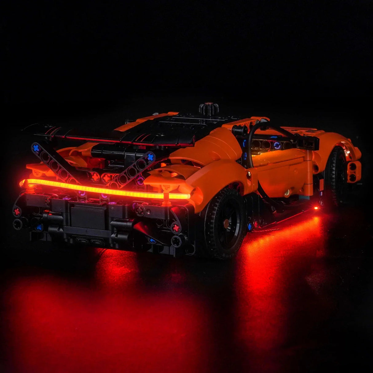 Orangefarbenes Spielzeugauto mit roten Lichtern auf schwarzem Hintergrund