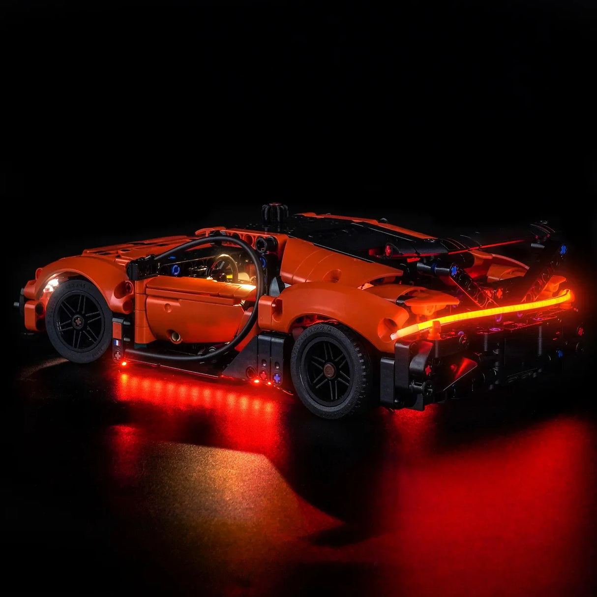 Orangefarbenes Spielzeugauto mit roten Lichtern auf schwarzem Hintergrund