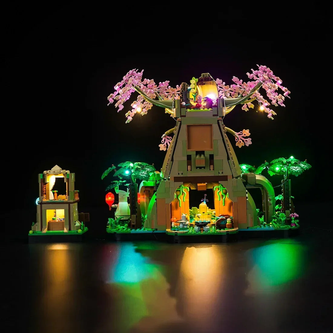 Beleuchtetes Lego Set mit Baumhaus und kleiner Hütte vor schwarzem Hintergrund