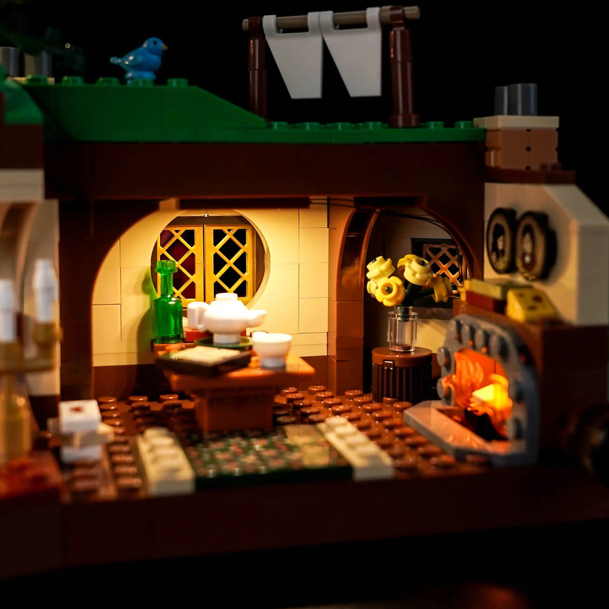 Ein beleuchtetes Lego-Haus mit einem blauen Vogel auf dem Dach und einem Kamin mit Feuer