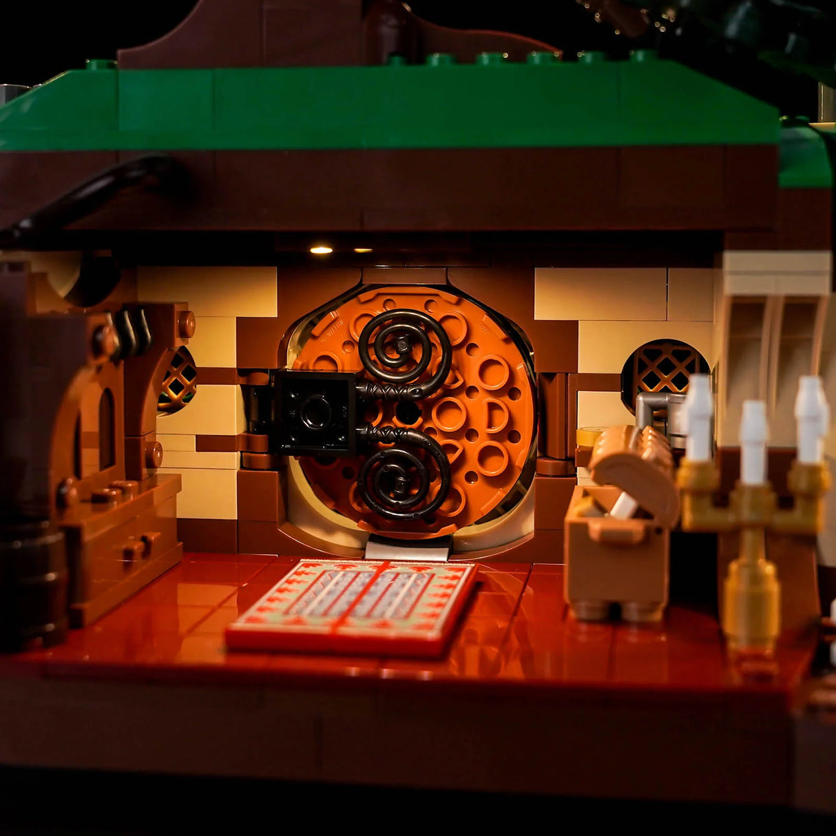Nahaufnahme eines Lego-Modells mit einem runden orangefarbenen Tor, einem roten Teppich und Kerzenständern
