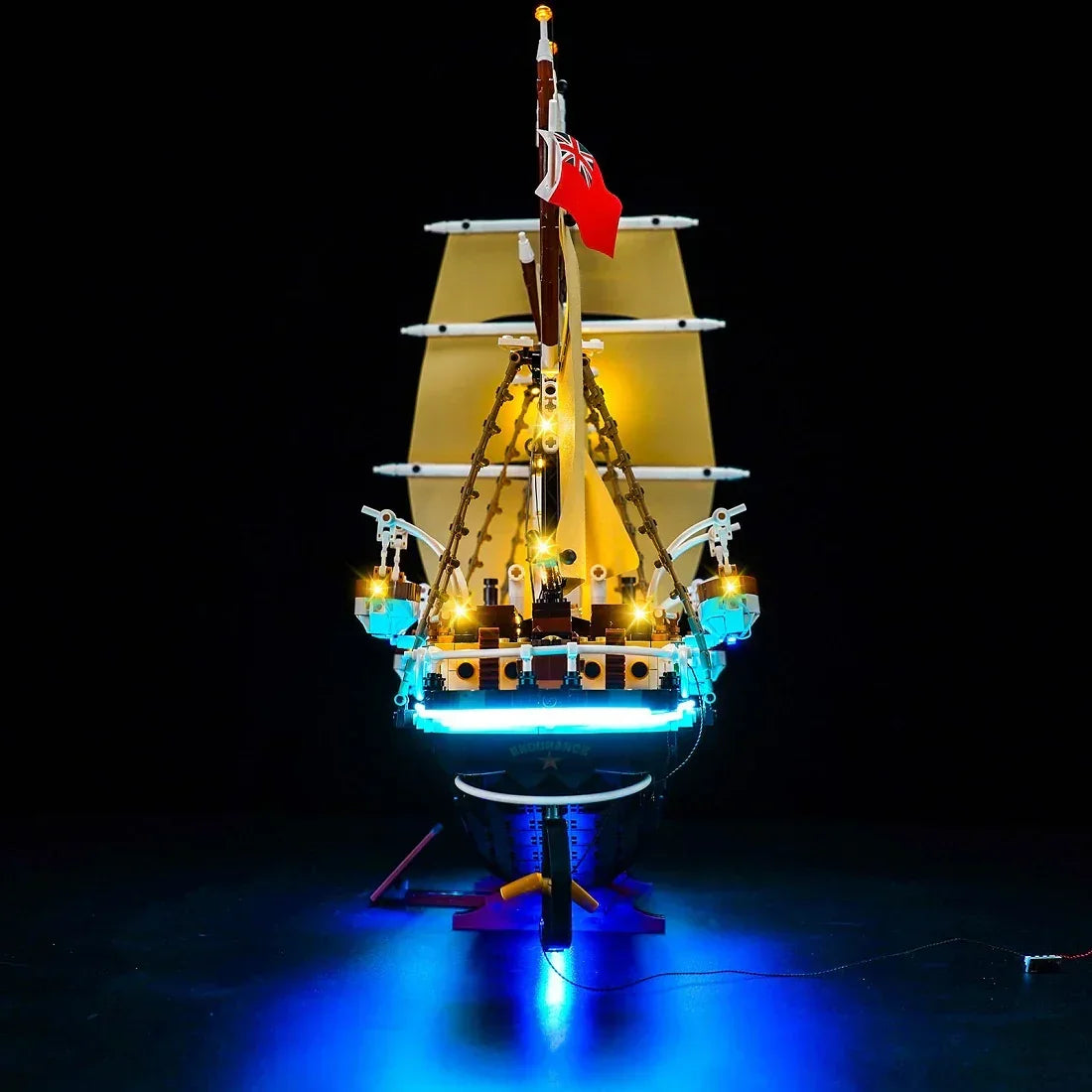 Beleuchtetes LEGO Schiff mit Segeln und roter Flagge auf schwarzem Hintergrund