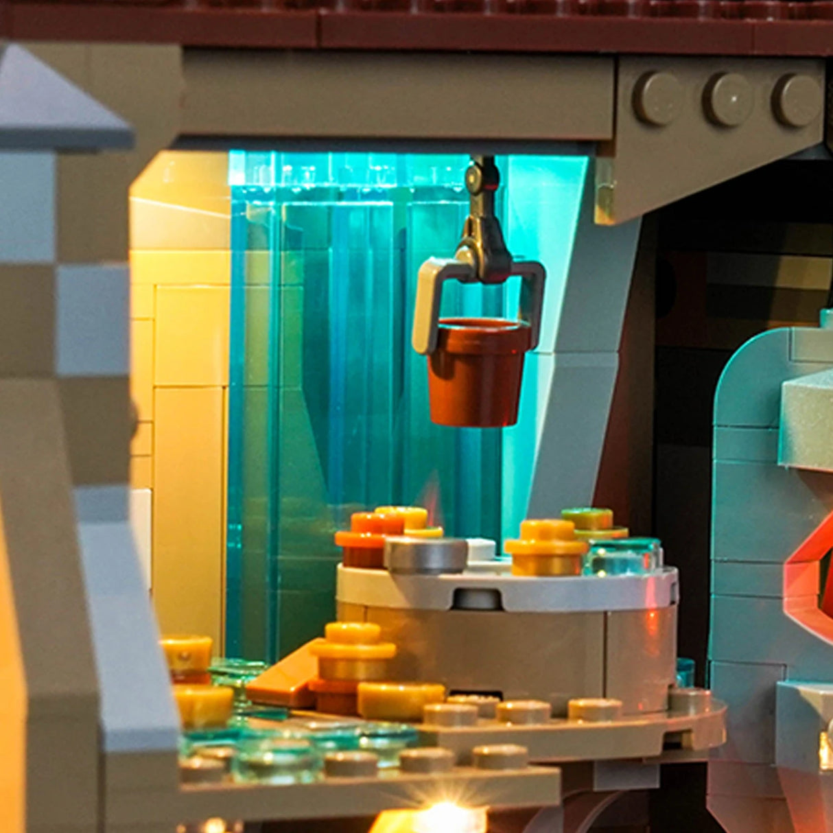 Nahaufnahme eines Lego-Sets mit einem Eimer, der von einem Kran über einem Tisch mit kleinen runden Steinen hängt