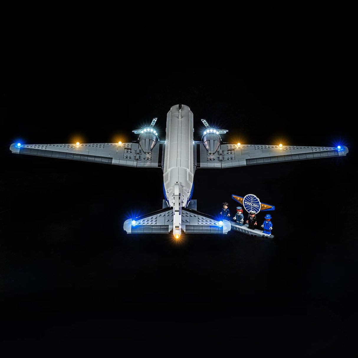 Beleuchtetes LEGO Flugzeugmodell mit Pan Am Logo und vier Minifiguren auf schwarzem Hintergrund
