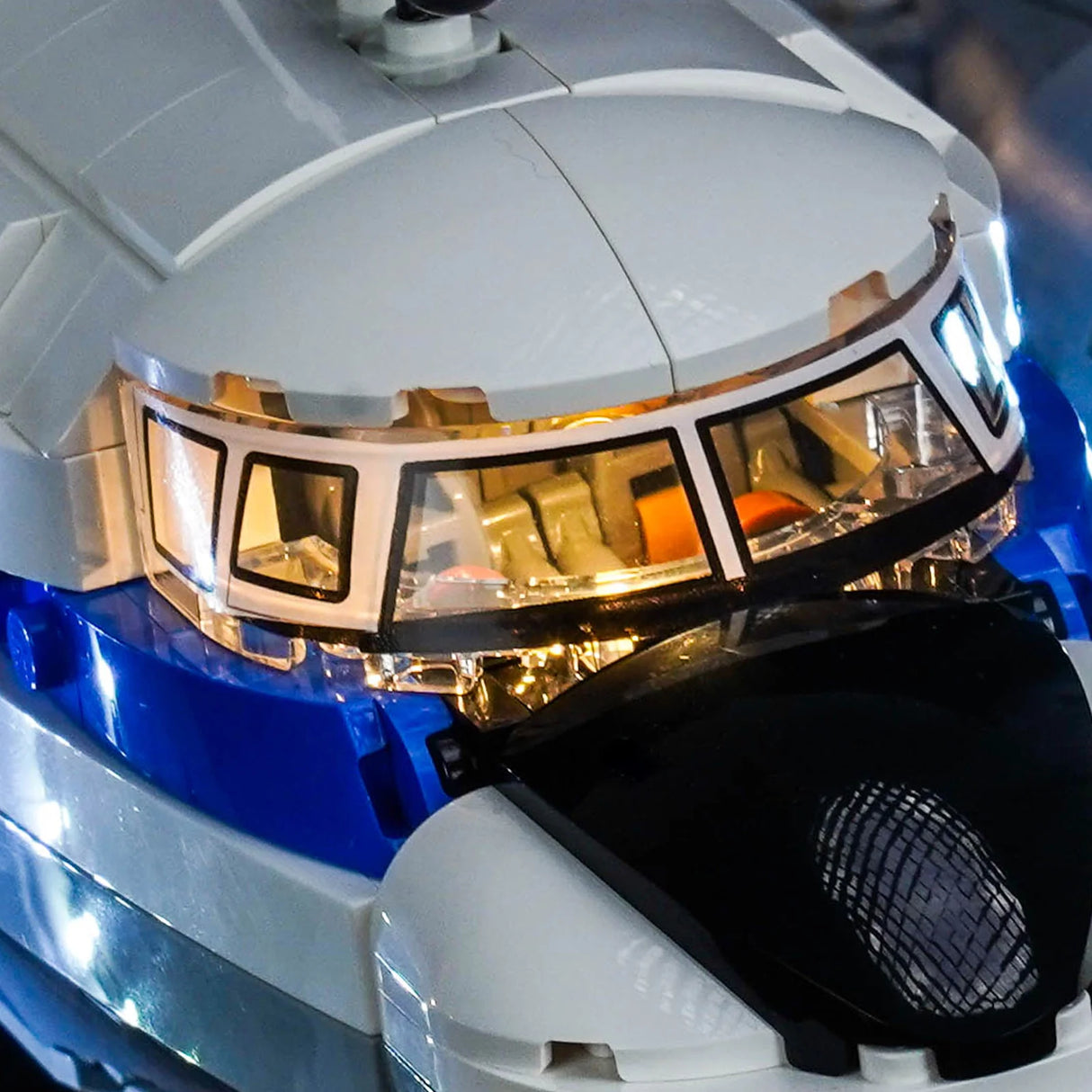 Nahaufnahme des Cockpits eines weißen und blauen Lego-Flugzeugs mit Lichtern, die durch die Fenster scheinen