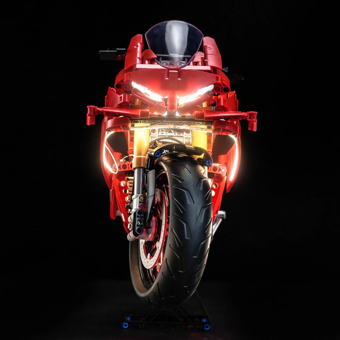 Rotes Motorradmodell mit leuchtenden Scheinwerfern und Vorderreifen auf schwarzem Hintergrund