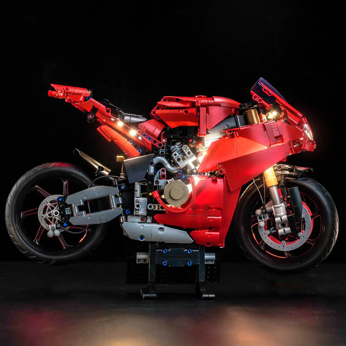 Rotes LEGO Technic Motorradmodell mit leuchtenden Lichtern auf schwarzem Hintergrund