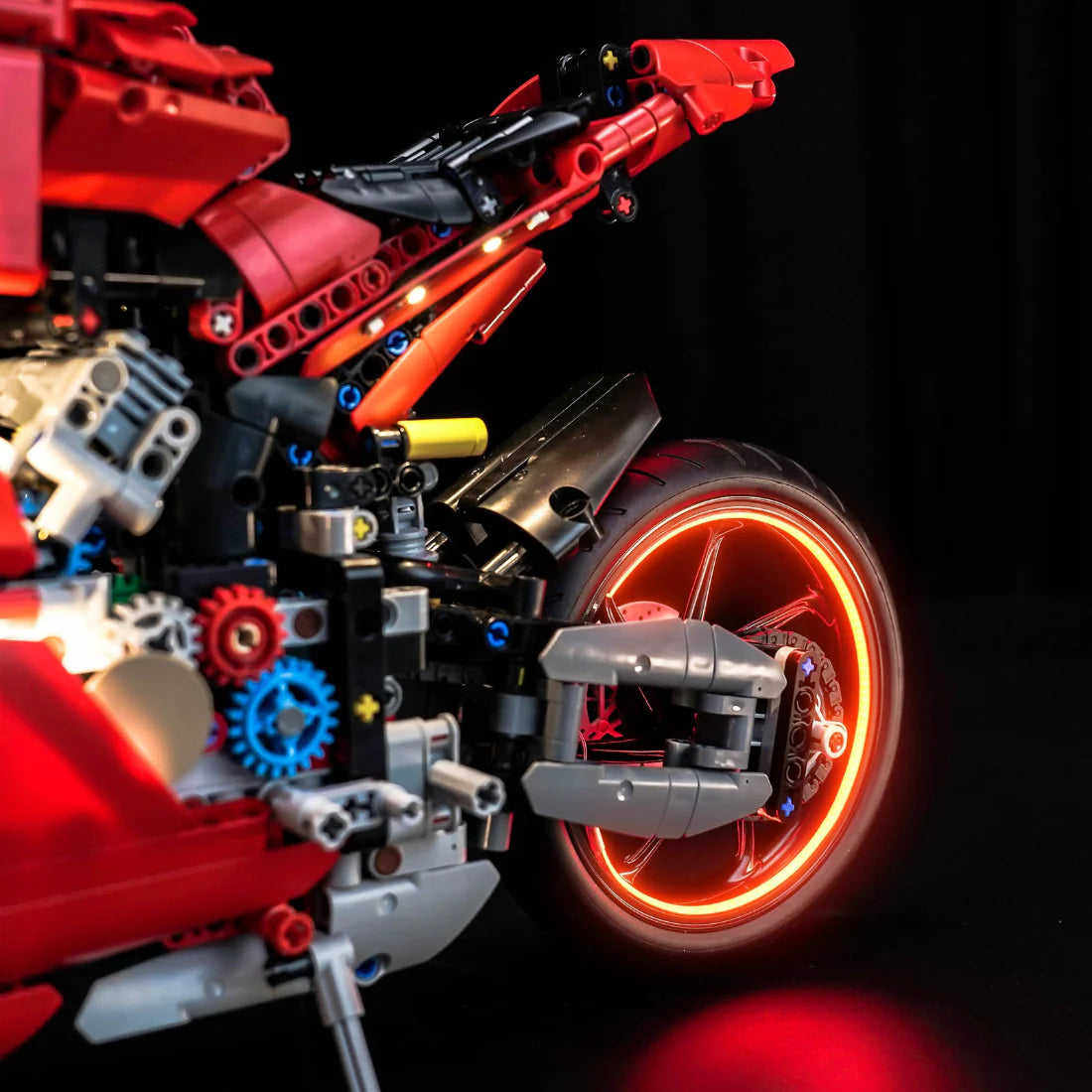 Rotes Lego Technic Motorrad mit leuchtendem Hinterrad auf schwarzem Hintergrund