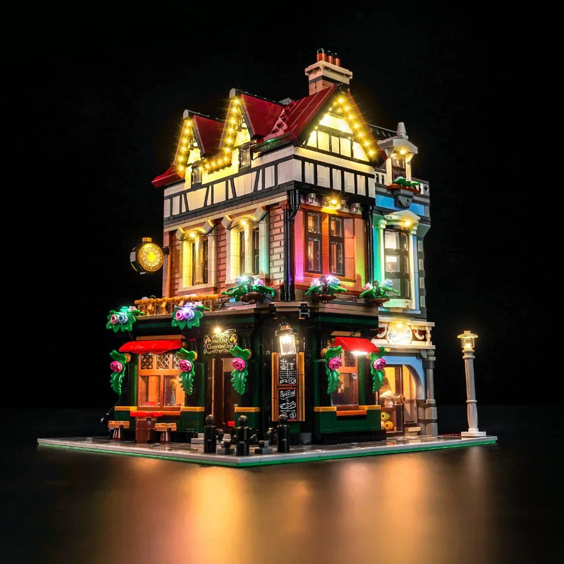 Beleuchtetes Lego-Modell eines Gasthauses mit roten Dächern und bunten Fenstern