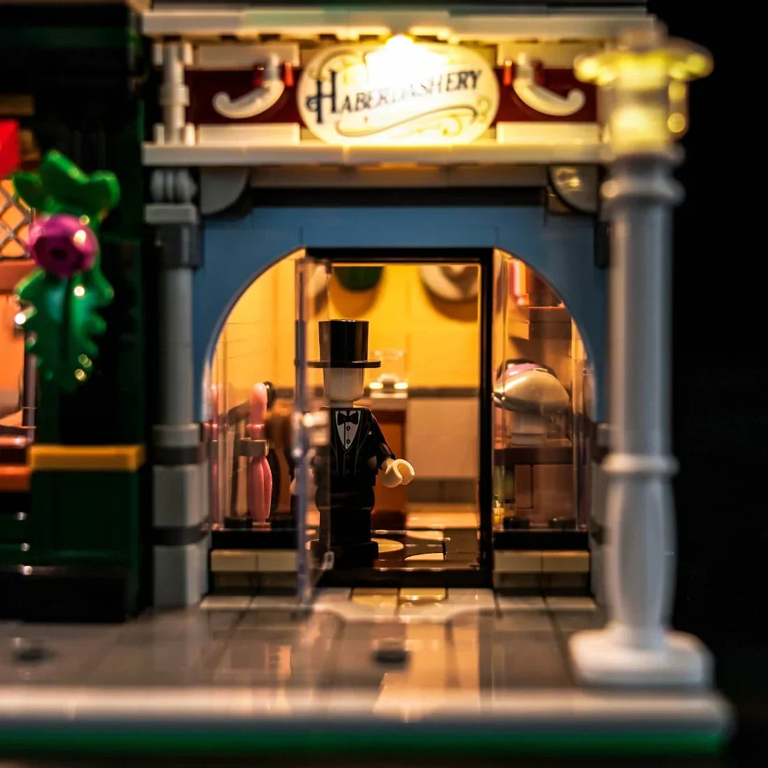 Lego-Figur in einem Zylinder und Anzug vor einem beleuchteten Laden mit der Aufschrift Haberdashery