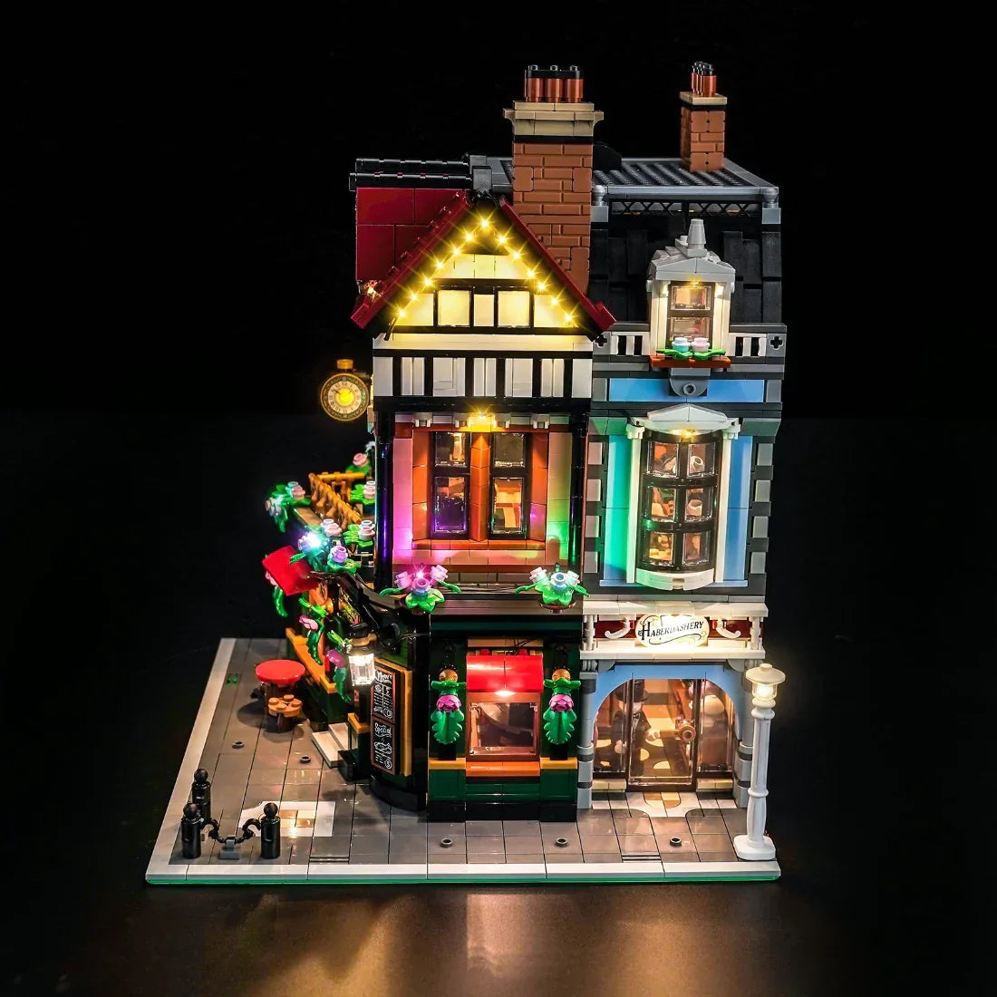 Beleuchtetes Lego-Gebäude mit zwei Geschäften und Wohnungen darüber bei Nacht