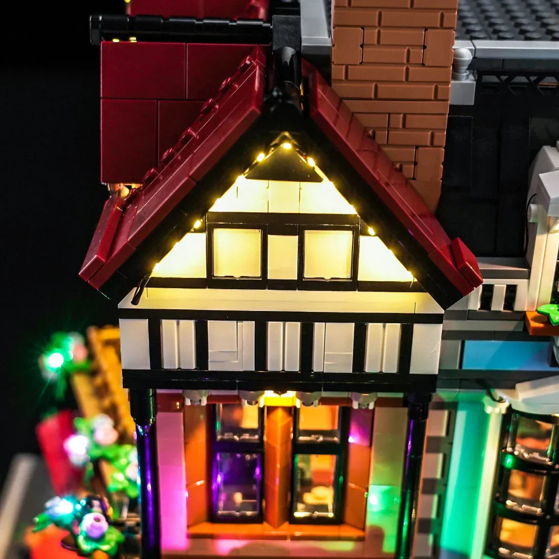Nahaufnahme eines beleuchteten Lego-Hauses mit roten Dächern und leuchtenden Fenstern
