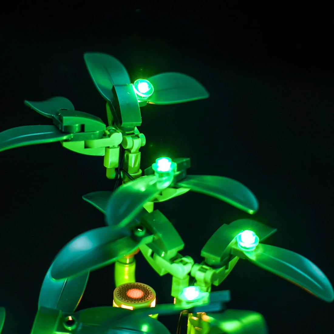 Nahaufnahme von grünen LEGO-Pflanzen mit leuchtenden grünen Lichtern auf schwarzem Hintergrund