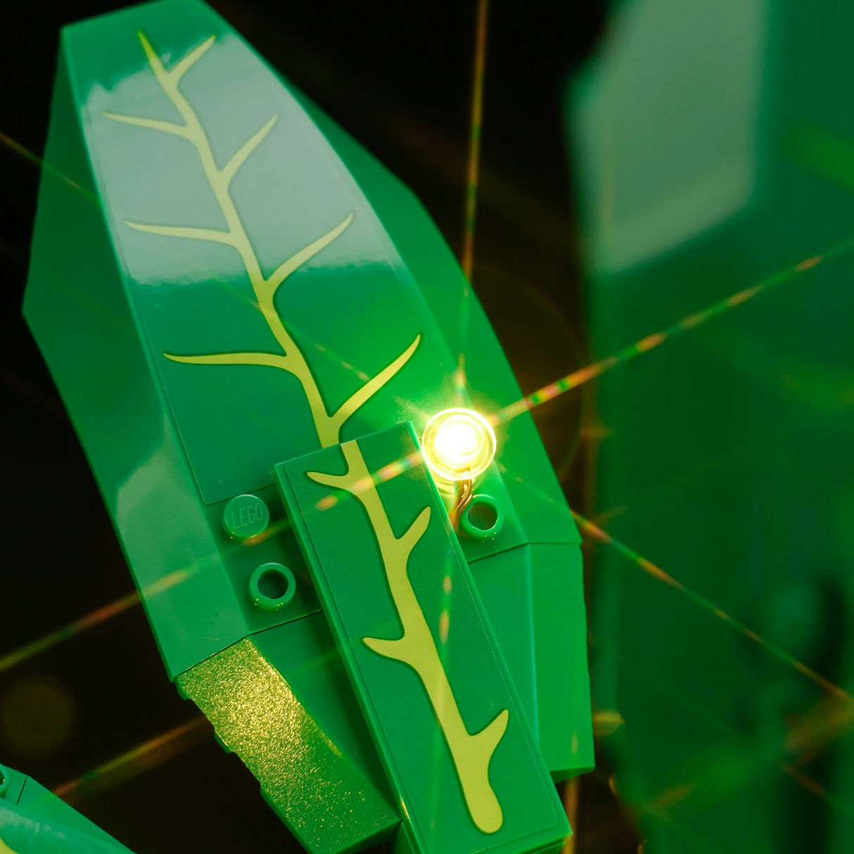 Nahaufnahme eines grünen LEGO-Blattes mit gelben Adern und einem leuchtenden Licht