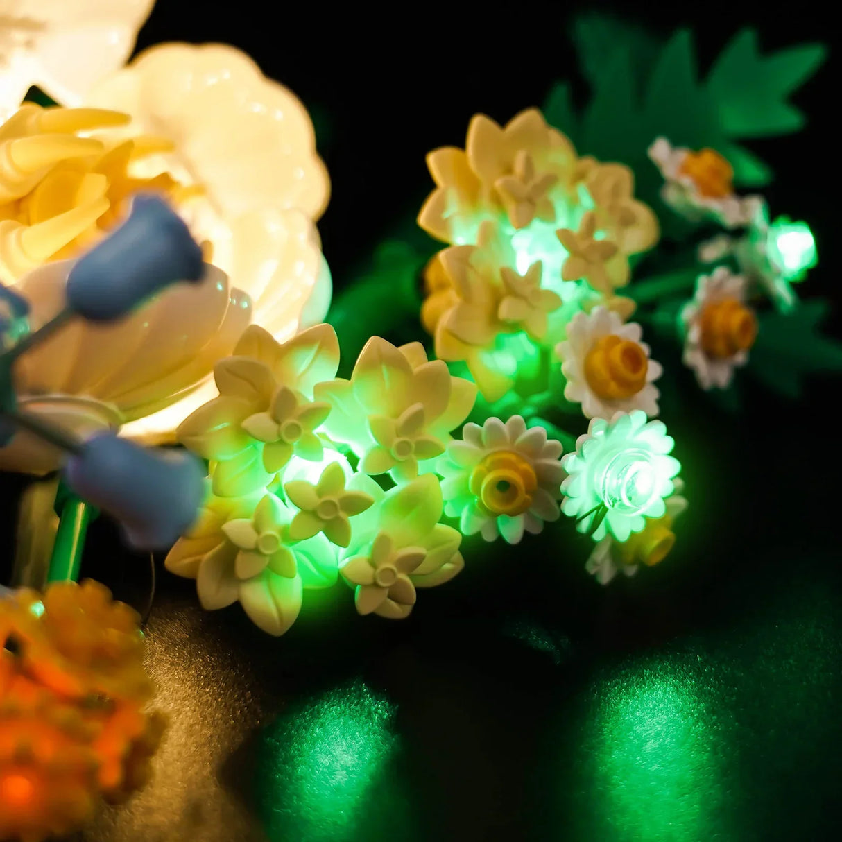 Nahaufnahme von leuchtenden Blumenlichtern in Gelb, Weiß und Grün auf dunklem Hintergrund