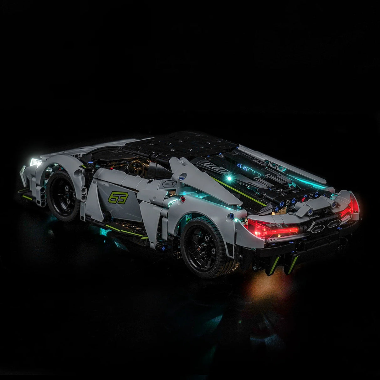 Graues Spielzeugauto mit leuchtenden Scheinwerfern und Rücklichtern auf schwarzem Hintergrund