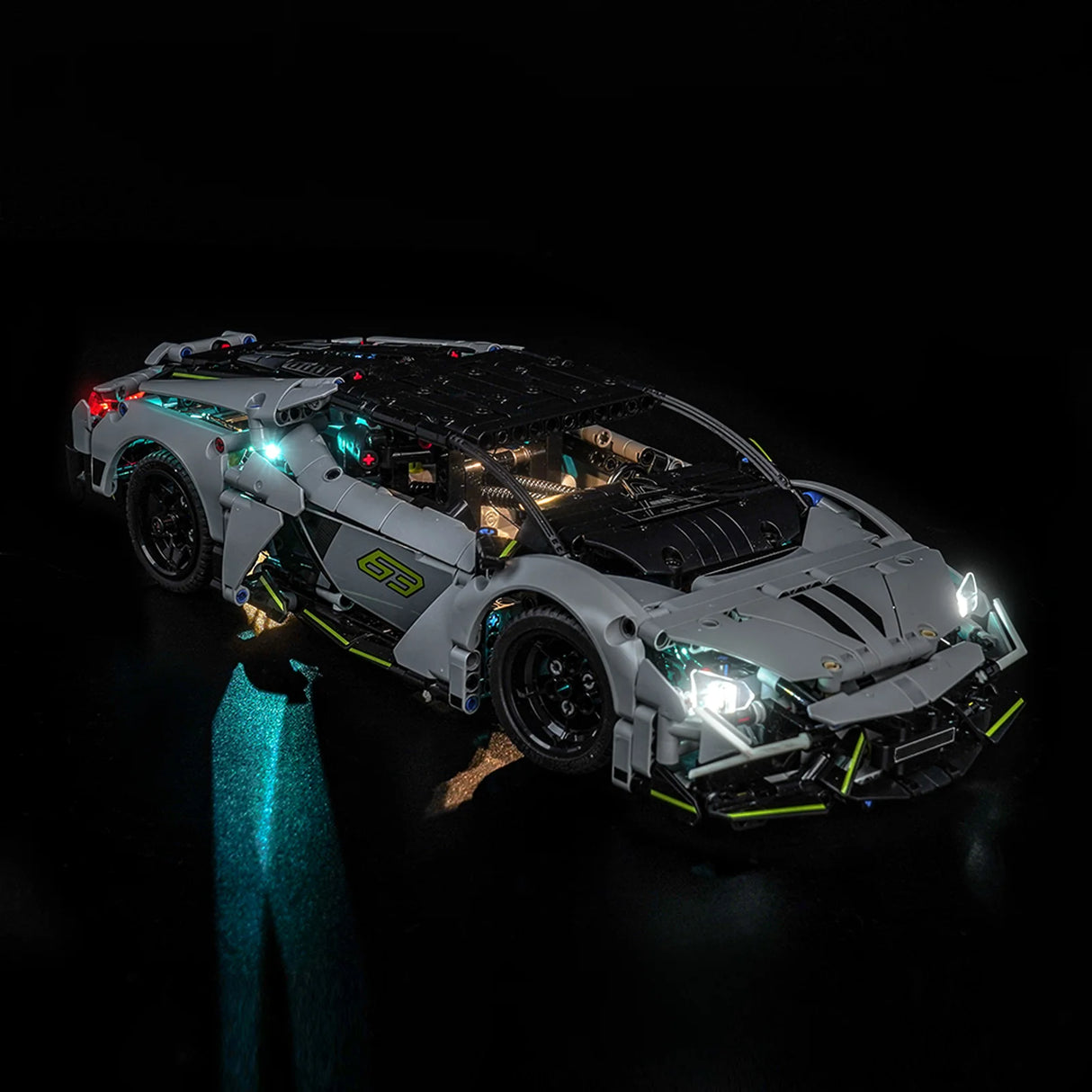 Graues Spielzeugauto mit leuchtenden Scheinwerfern und Rücklichtern auf schwarzem Hintergrund