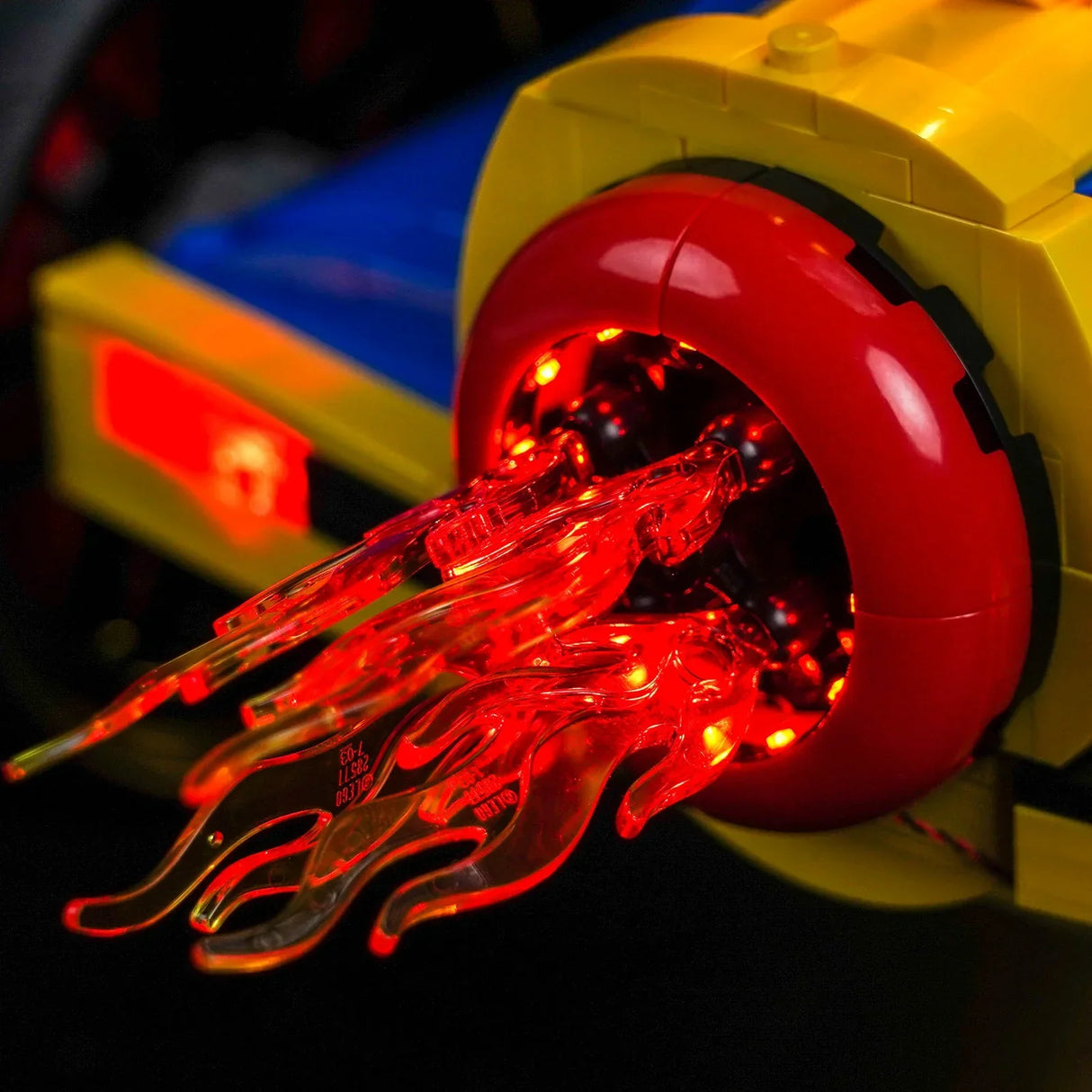 Nahaufnahme eines gelben und blauen Lego-Modells mit einem roten Triebwerk, das rote Flammen ausstößt