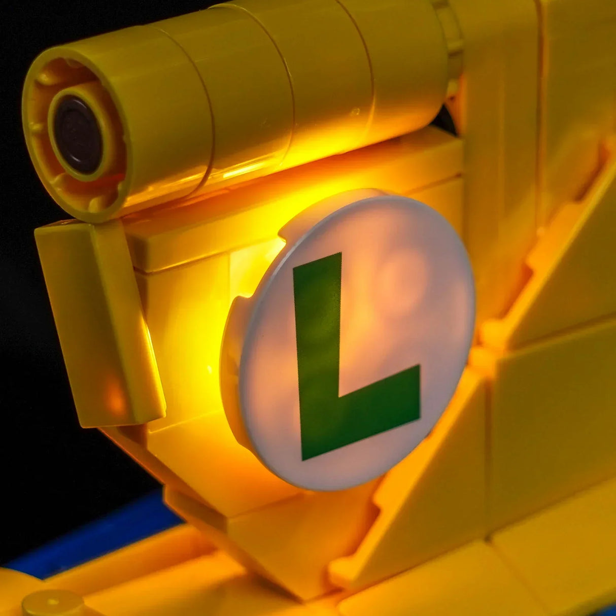 Nahaufnahme eines gelben Lego-Objekts mit einem leuchtenden runden weißen Schild, das ein grünes L zeigt