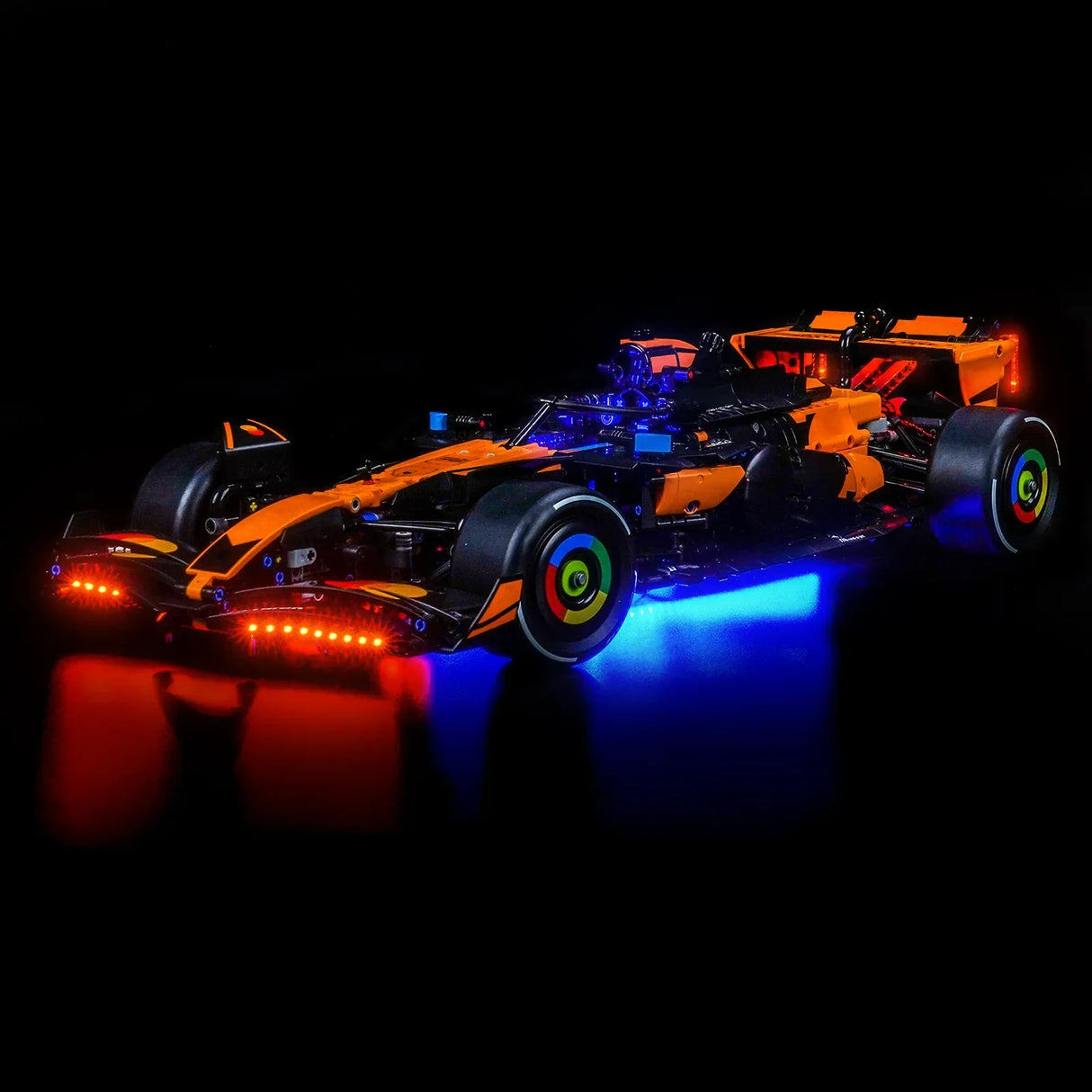 Orange-schwarzes Formel-1-Modellauto mit roten und blauen Lichtern auf schwarzem Hintergrund