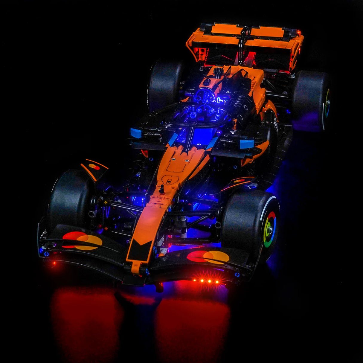 Orangefarbenes und schwarzes Formel-1-Modellauto mit blauer und roter Beleuchtung auf schwarzem Hintergrund