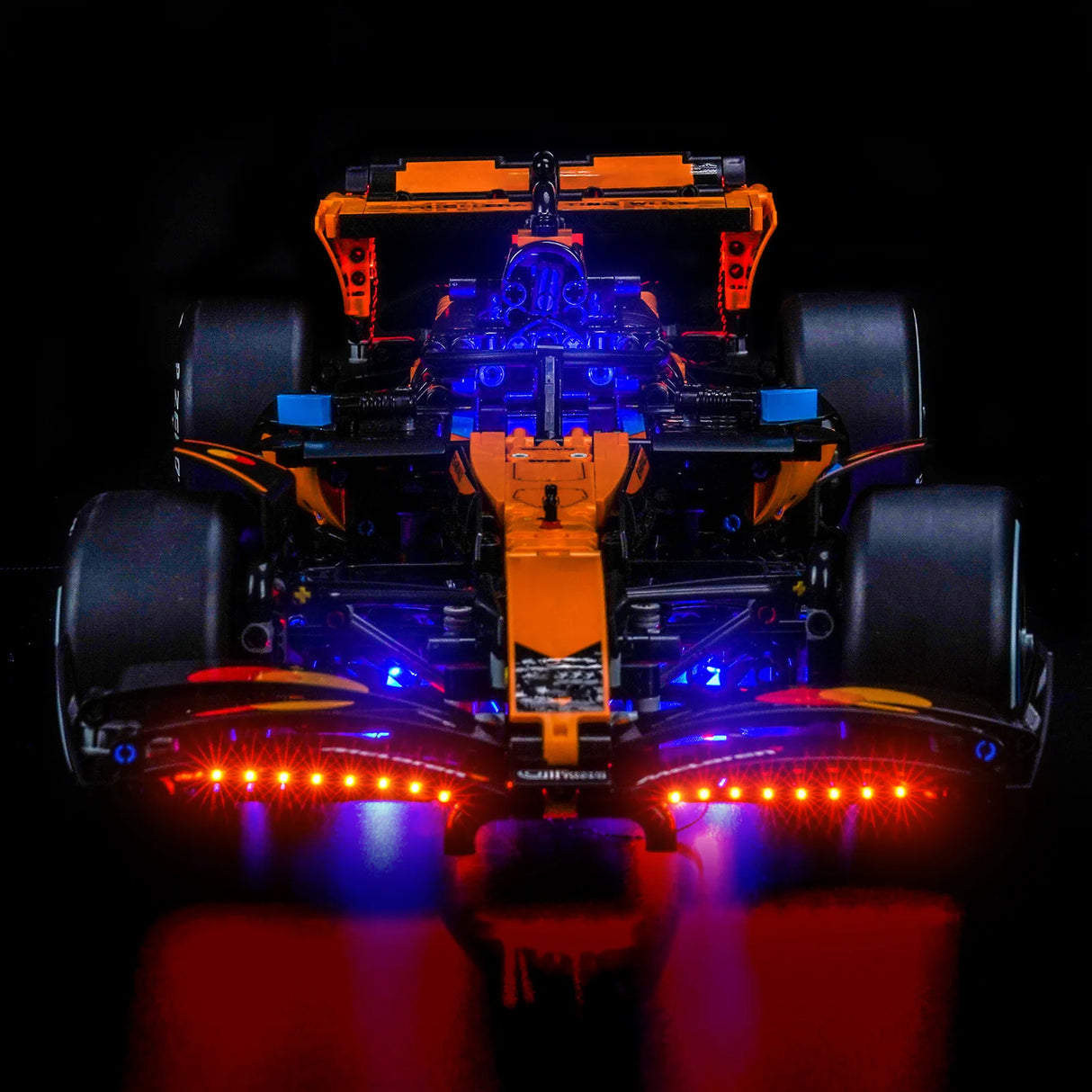 Orangefarbenes Formel-1-Modellauto mit blauen und roten Lichtern auf schwarzem Hintergrund