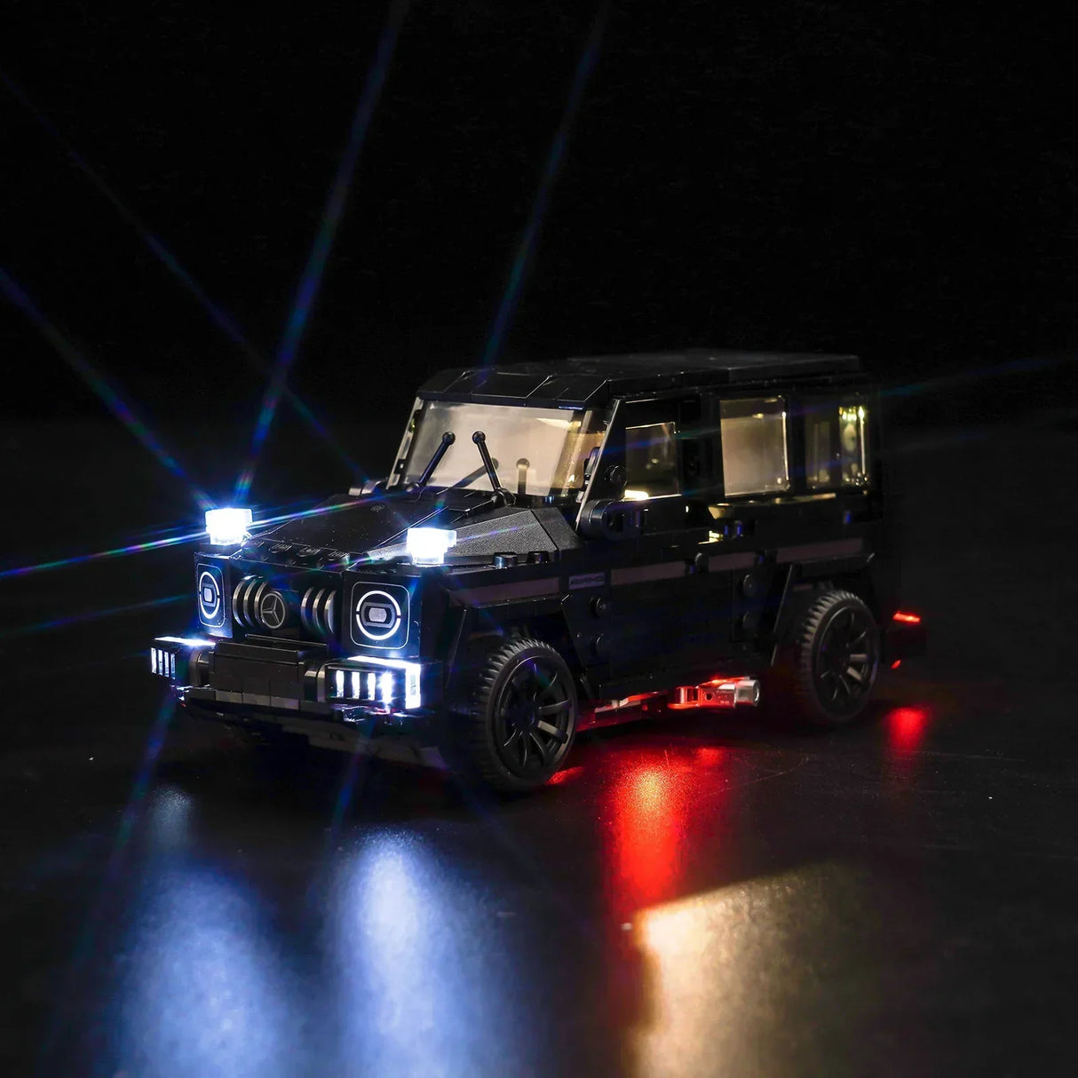 Schwarzes Mercedes G-Klasse Modellauto aus Klemmbausteinen mit eingeschalteter LED Beleuchtung vor schwarzem Hintergrund