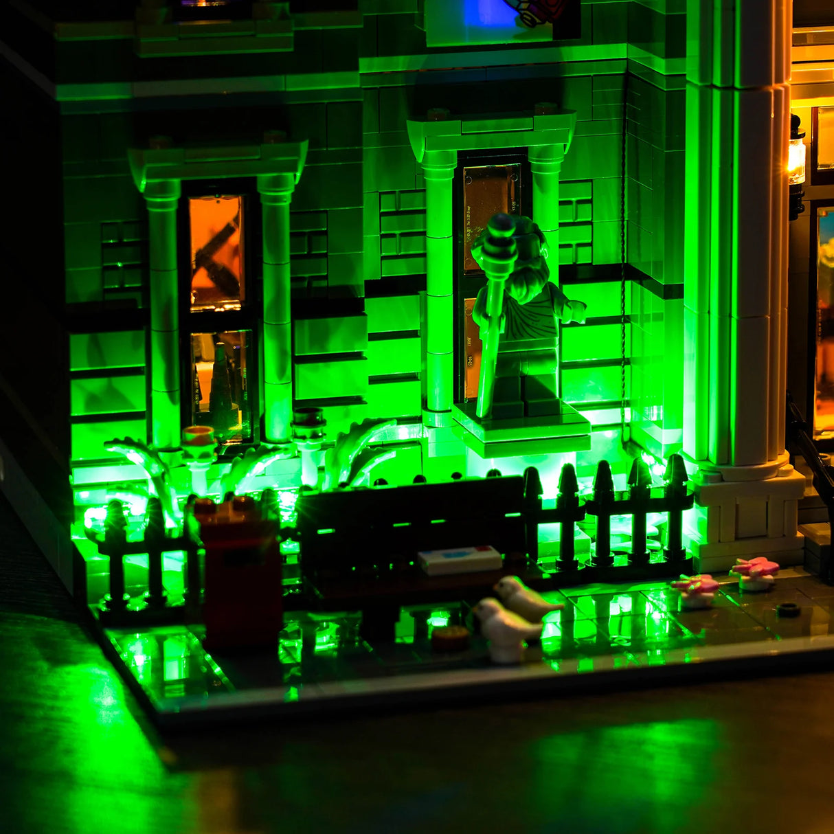 Grün beleuchtetes Lego-Gebäude mit Säulen, einem Zaun und einer Minifigur, die einen Stab hält