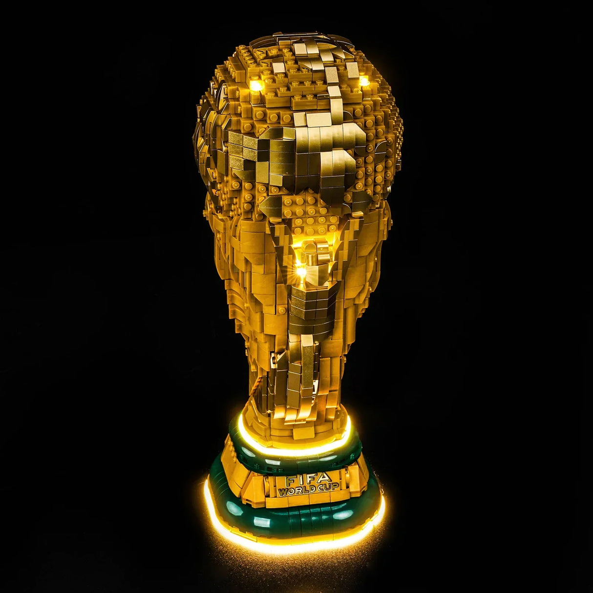 Beleuchtete goldene FIFA World Cup Trophäe aus Legosteinen auf schwarzem Hintergrund