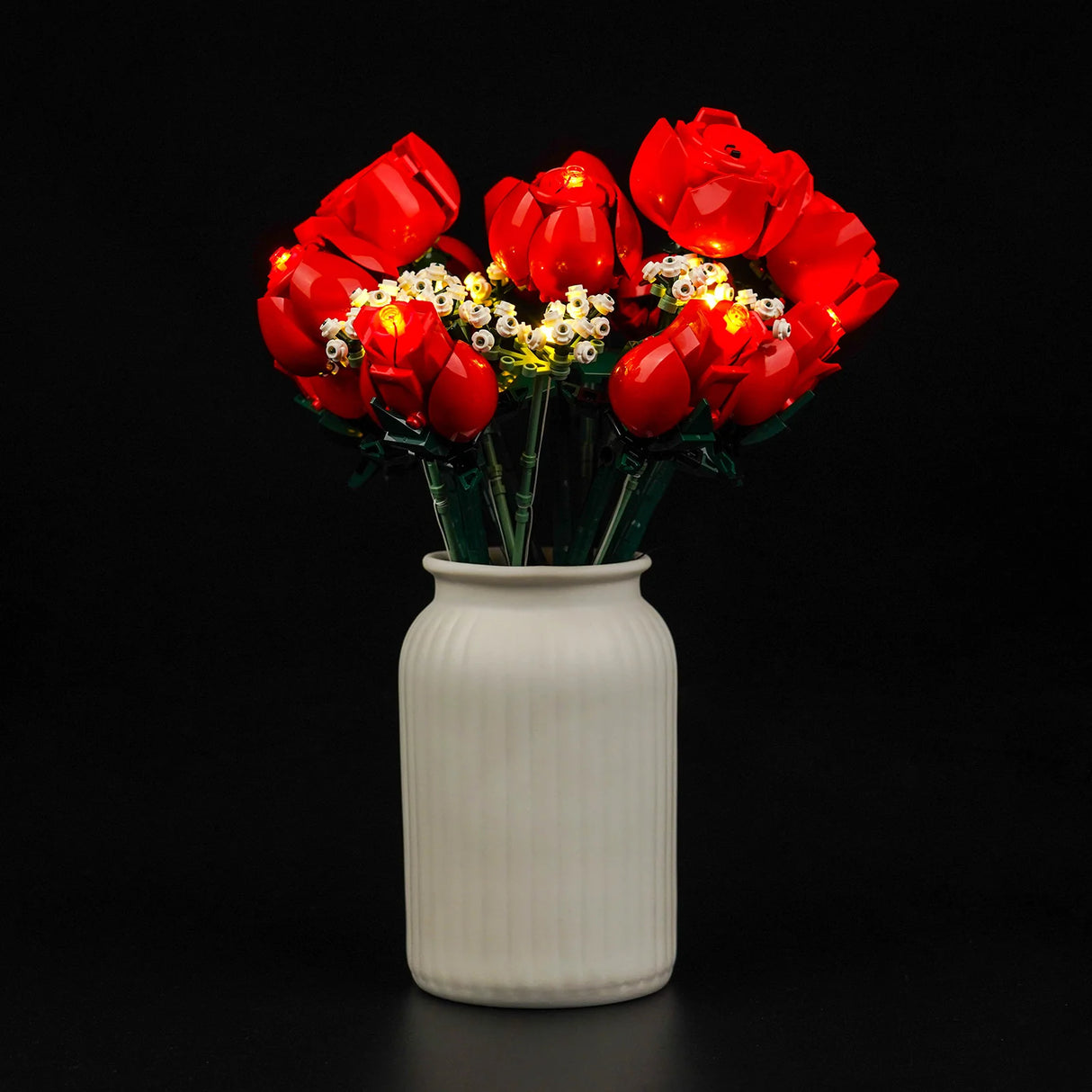 Ein Strauß leuchtender roter Rosen und weißer Blüten in einer weißen Vase