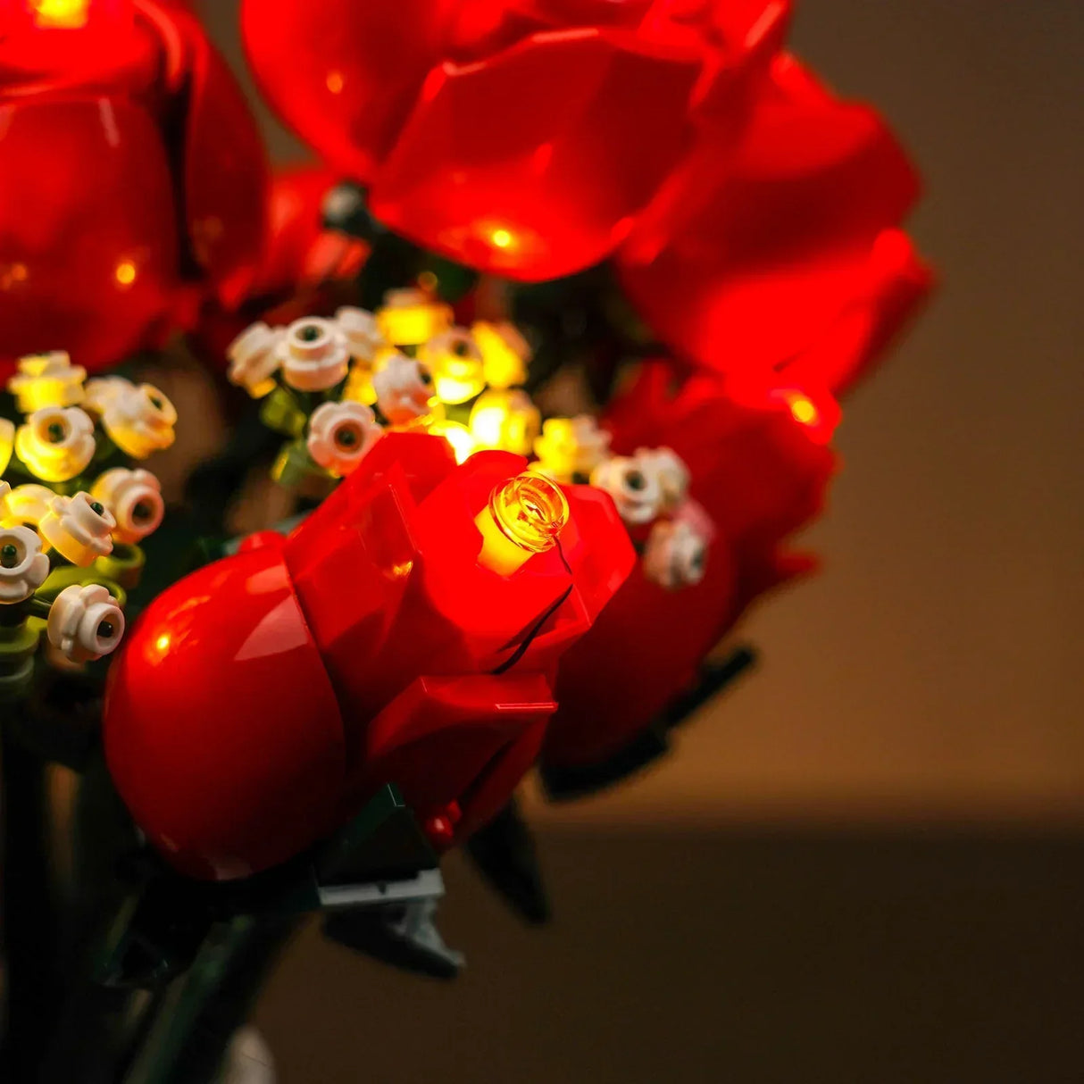 Nahaufnahme eines Blumenstraußes aus roten Rosen und weißen Blüten mit gelben Lichtern