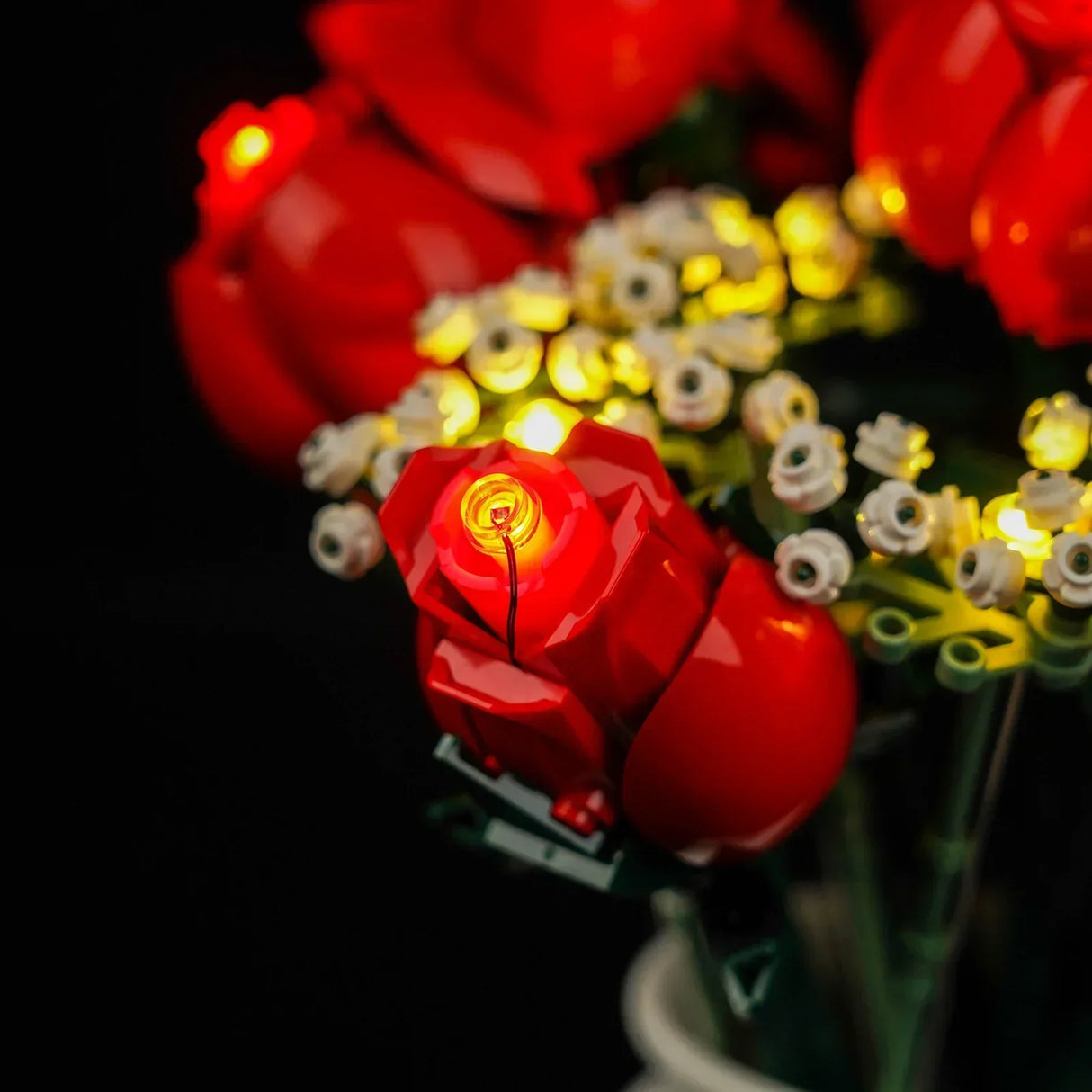 Nahaufnahme eines leuchtenden roten Rosenstraußes aus Bausteinen mit kleinen weißen Blüten
