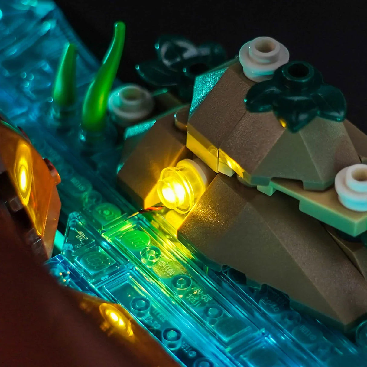 Nahaufnahme von leuchtenden LEGO-Steinen in Blau, Grün und Gelb, die eine Landschaft mit Wasser und Felsen darstellen