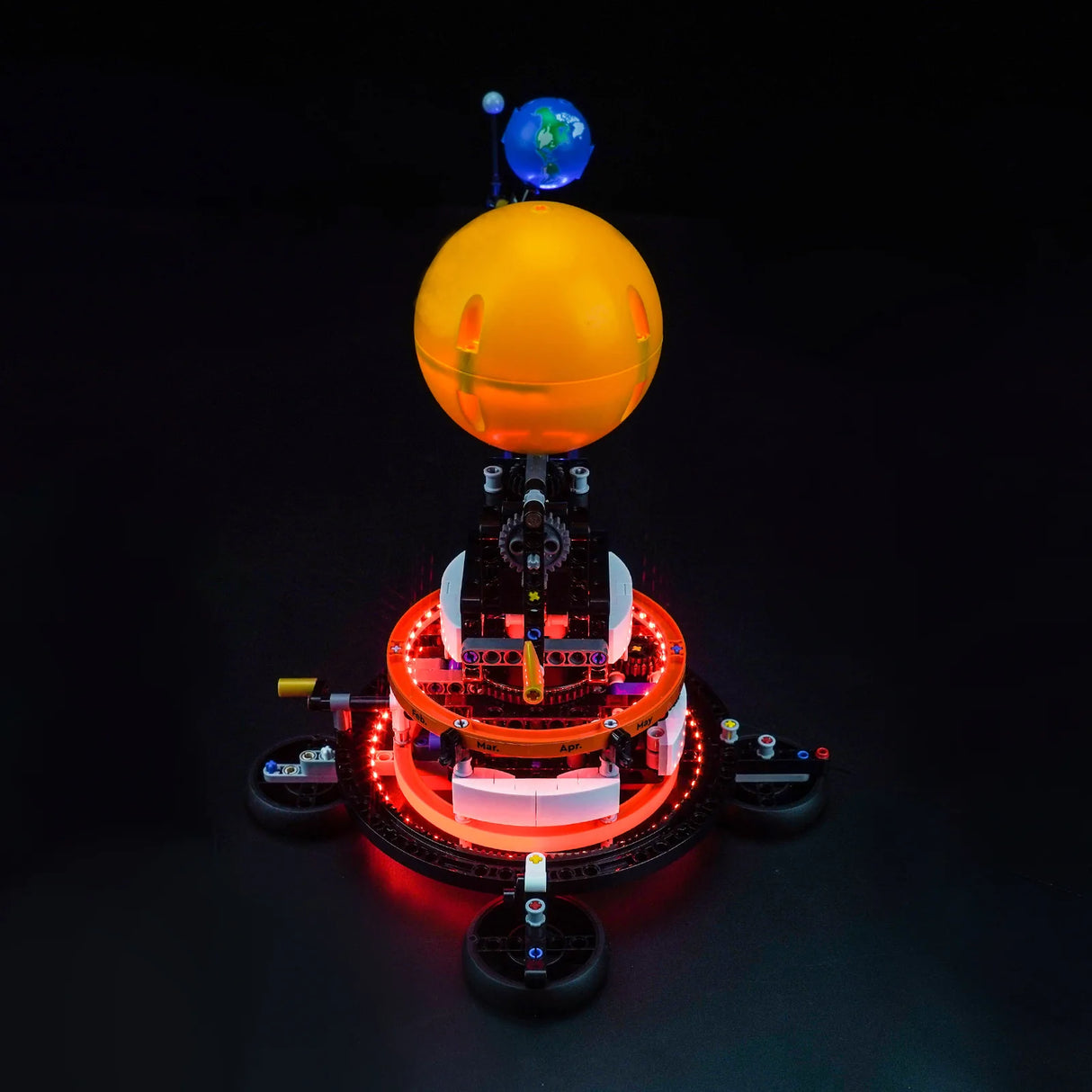 Beleuchtetes Modell des Sonnensystems mit Sonne und Erde vor schwarzem Hintergrund