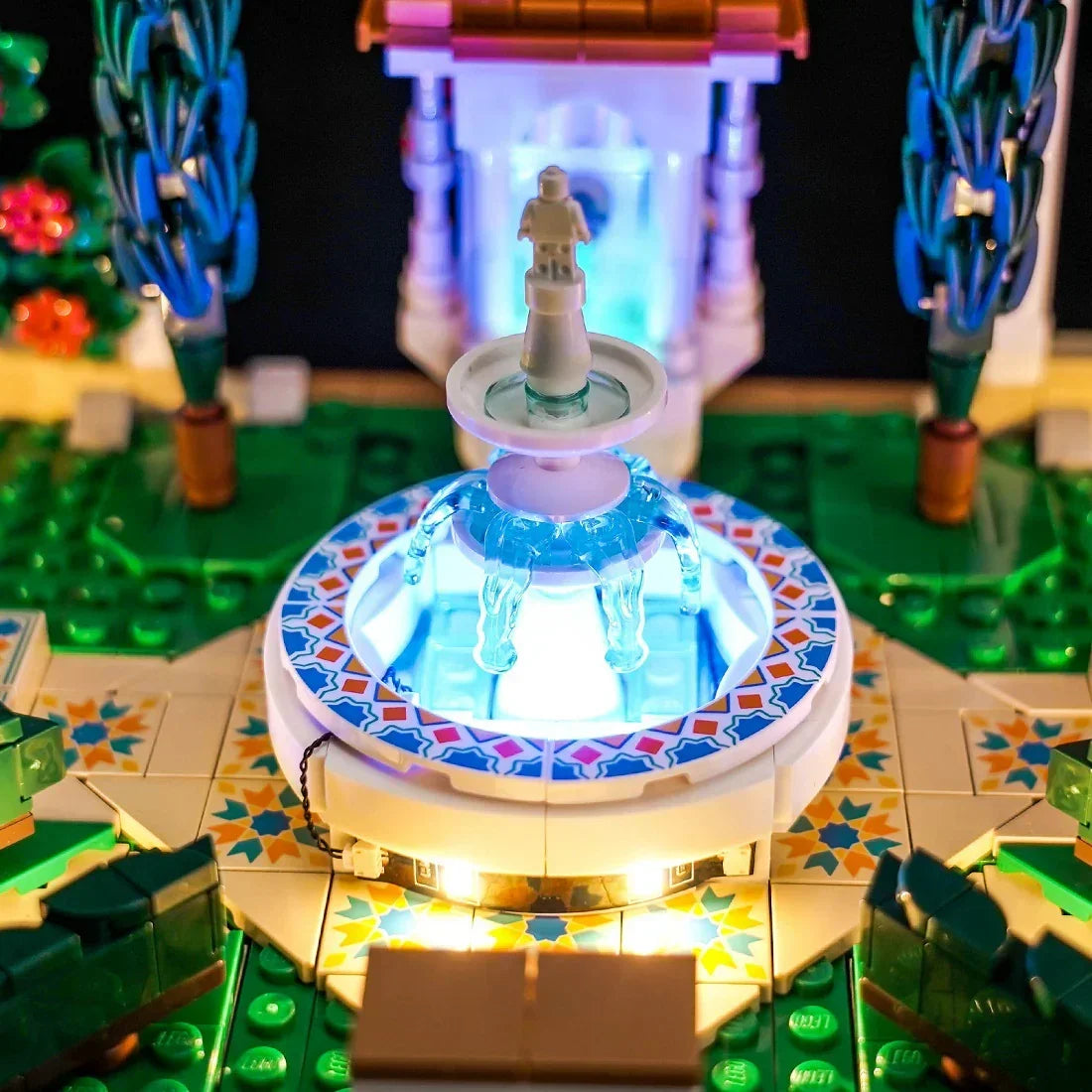 Beleuchteter Lego-Brunnen mit blauen Lichtern und einer kleinen Figur in einem Garten