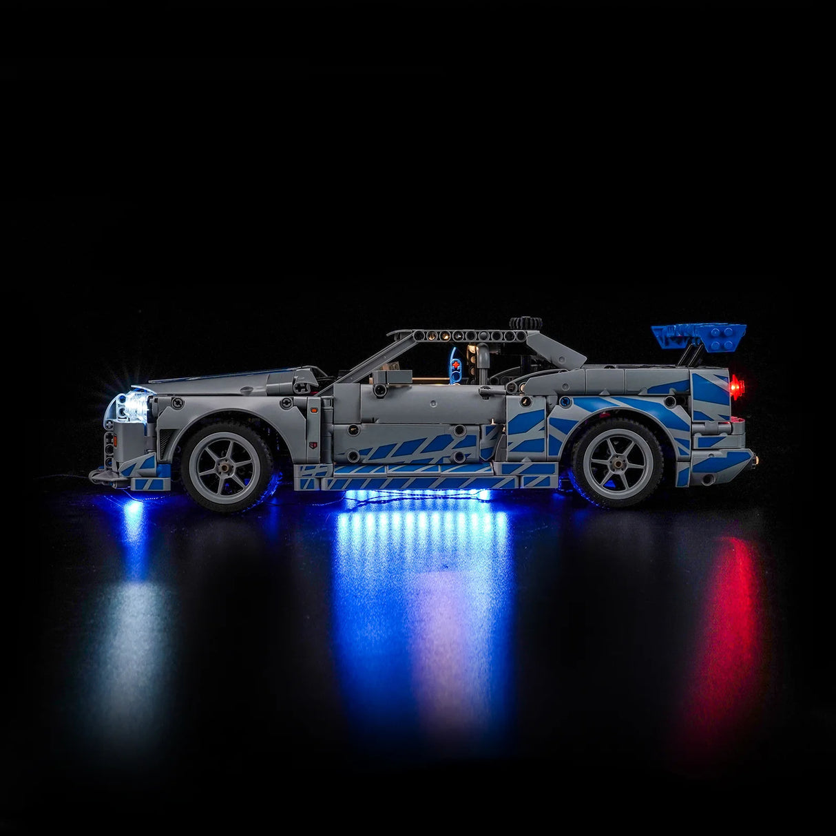 Graues Spielzeugauto mit blauen Mustern und leuchtenden Lichtern auf schwarzem Hintergrund