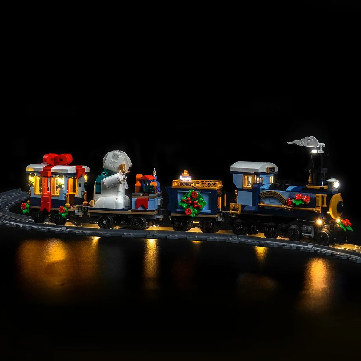 Beleuchteter LEGO Holiday Express Zug mit Geschenken und Schneemann auf Schienen im Dunkeln