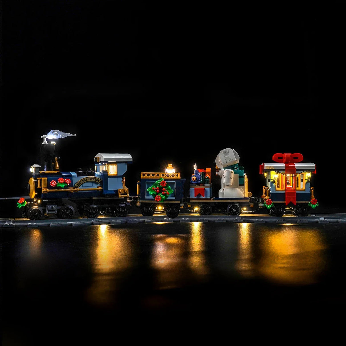 Beleuchteter Holiday Express Zug mit Geschenken und Kränzen auf Schienen im Dunkeln