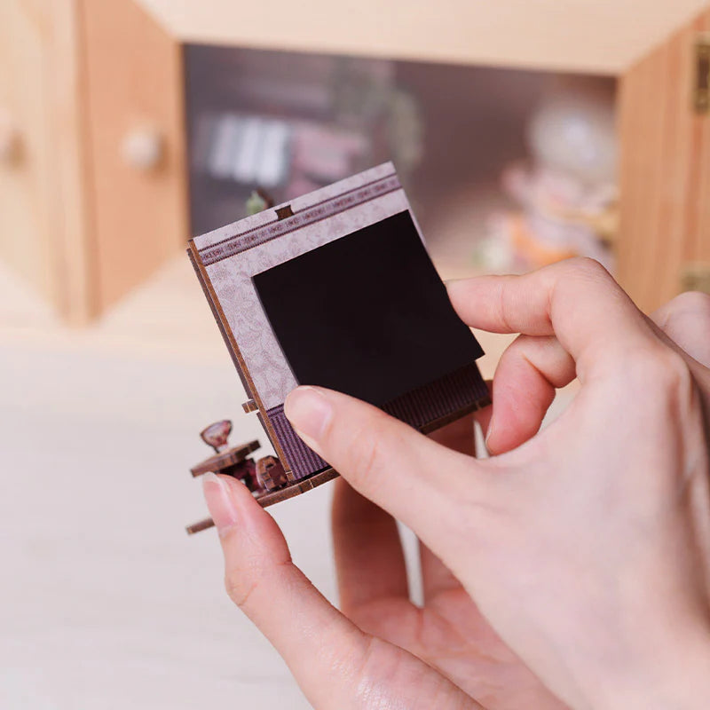 Hände halten ein Miniatur-Diorama mit einem schwarzen Rechteck in der Mitte