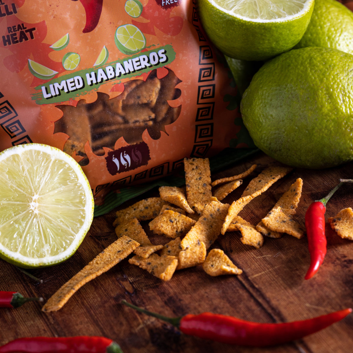 Tüte Limed Habaneros Chips mit Limetten und Chilischoten auf Holzbrett